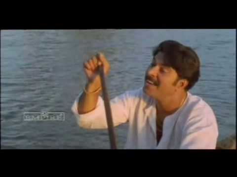 Mammootty paddling while wearing white long sleeves and bracelet in a scene from the 1996 film, Azhakiya Ravanan