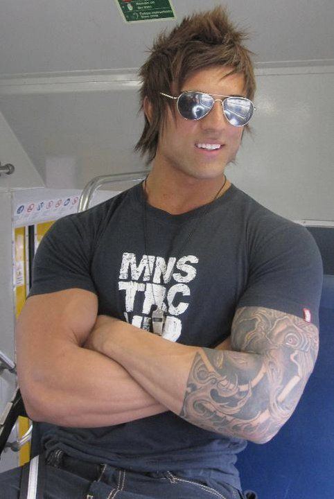 Aziz Shavershian smiling, wearing sunglasses and a tight shirt.