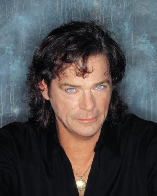B. J. Thomas with long wavy hair and wearing a necklace and black shirt.