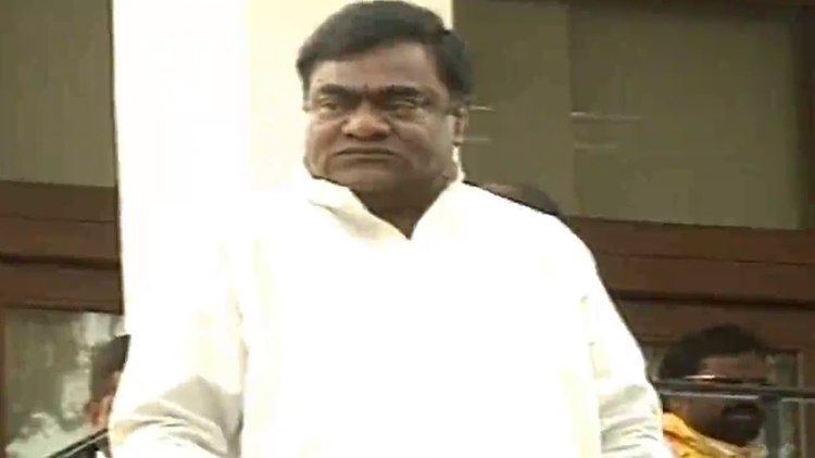 Babu Mohan looking afar while wearing a white long sleeves