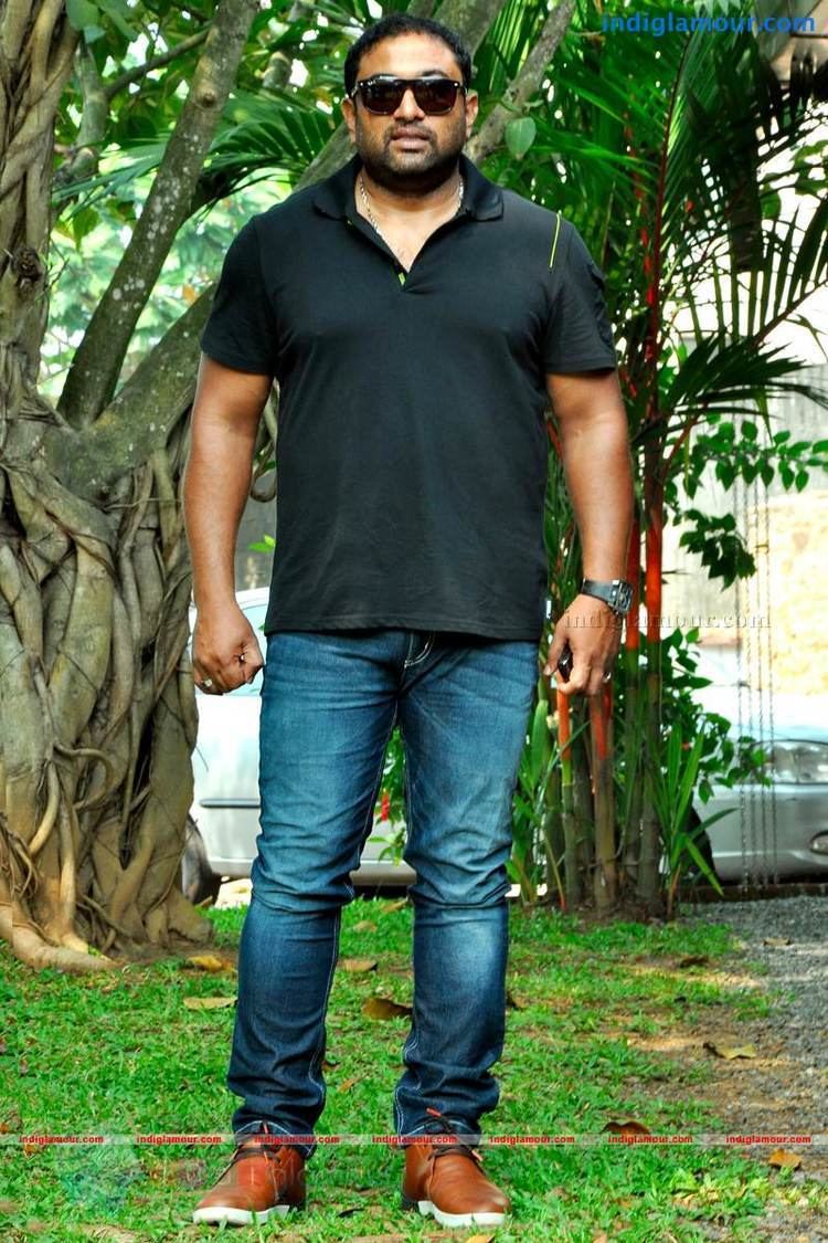 Baburaj wearing black shades, black polo shirt, jeans and brown shoes
