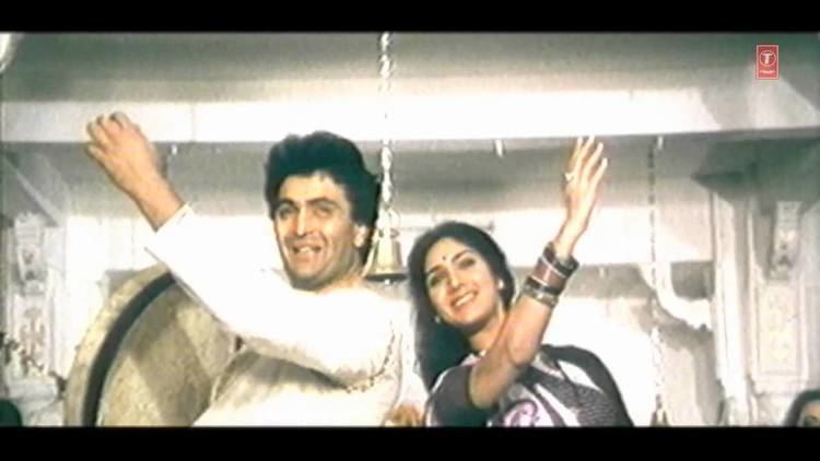 Meenakshi Seshadri and Rishi Kapoor smiling while dancing in a movie scene from the 1989 film Bade Ghar Ki Beti