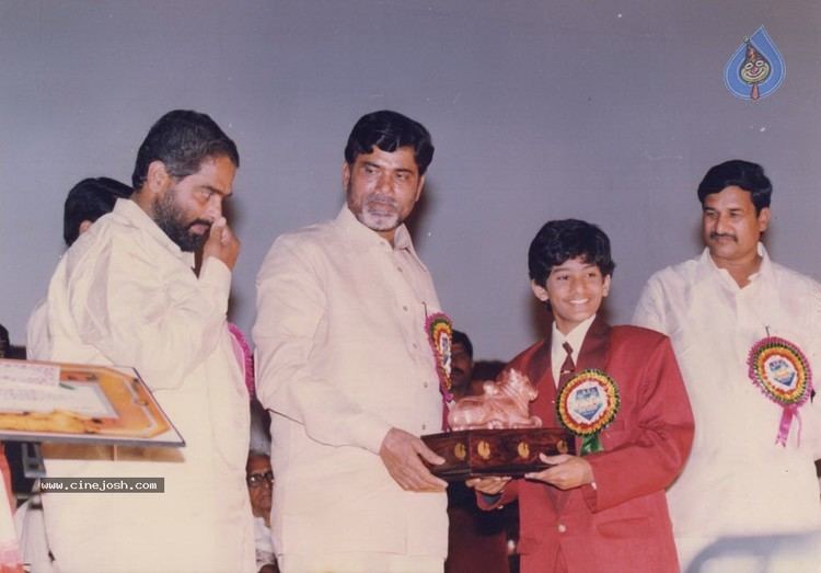 Young Baladitya wearing red coat and white long sleeves as he receives his award