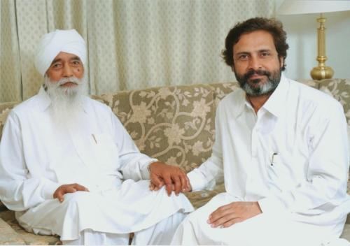 Baljit Singh (Sant Mat) with Sant Thankar Singh both wearing all-white shirt while sitting on a couch