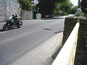 Captured a motorbike racing on a road at a  high speed with brick walls on its sides