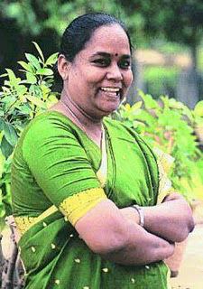 Bama smiling while her arms crossed and wearing a yellow and green dress, green dupatta, and wristwatch