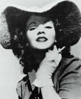 Barbara Daly Baekeland with curly hair and wearing a hat, gloves and blouse