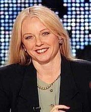 Barbara Olson smiling while wearing a black coat, green inner blouse, earrings, and necklace