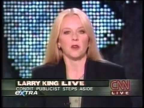 Barbara Olson reporting the news while wearing a black coat, green inner blouse, earrings, and necklace