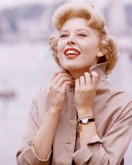 Barbara Ruick smiling while wearing a beige blazer, wristwatch, and bracelet