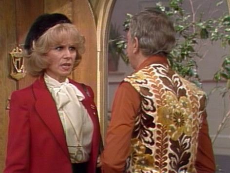 Barbara Stuart talking to Don Knotts while wearing a red coat and white blouse in a scene from the 1976 television series, Three's Company