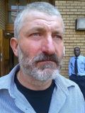 Barend Strydom with beard and mustache, and wearing a blue polo shirt and black shirt.