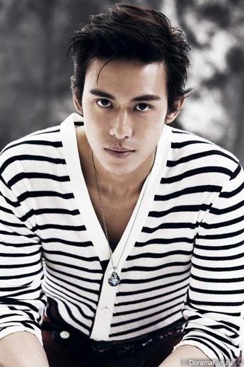 Baron Chen posing with short hair and wearing a black and white striped shirt and a necklace.