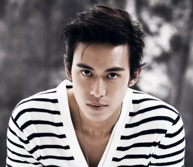 Baron Chen posing with short hair and wearing a black and white striped shirt and a necklace.