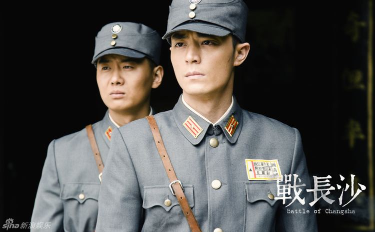 Wallace Huo with a serious face and wearing a gray uniform with another soldier on his back in a movie scene from Battle of Changsha (2014 Chinese TV Drama series).