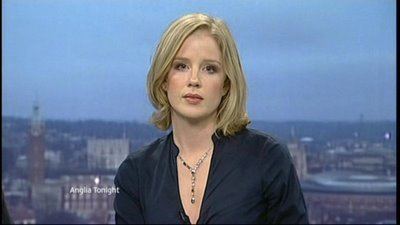 Becky Jago wearing a blue shirt and a necklace with short blonde hair in the CBBC children's news programme called "Newsround".