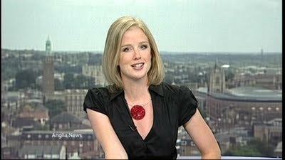 Becky Jago wearing a black shirt and a red necklace with short blonde hair in the CBBC children's news programme called "Newsround".