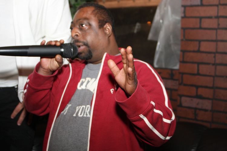 Beetlejuice holding a microphone, wearing a red jacket and a gray shirt.