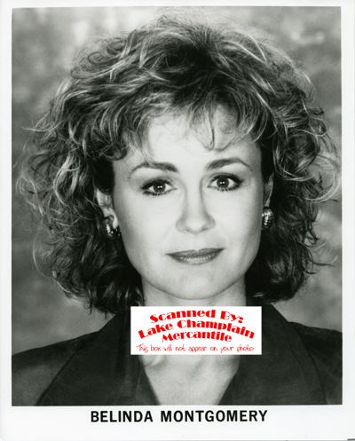 Belinda Montgomery with a tight-lipped smile and curly hair while wearing a blouse and earrings