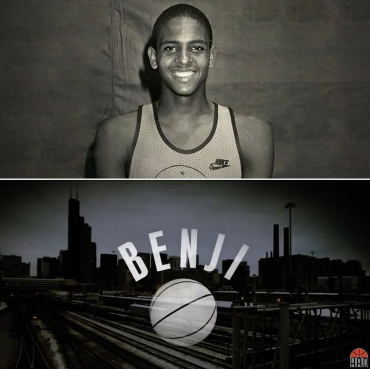 Smiling Ben Wilson wearing a basketball jersey on the upper, and a city with his name on the lower