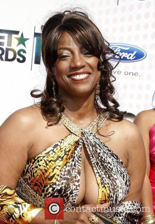 Bern Nadette Stanis smiling with curly hair while wearing an earrings and g...