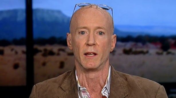 Bernard McGuirk with eyeglasses on his bald head, wearing a brown suit.