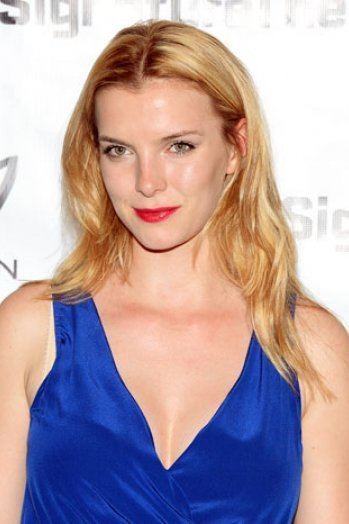 Betty Gilpin smiling while wearing a blue sleeveless dress