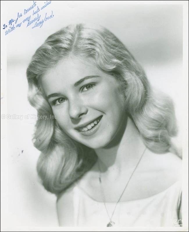 Beverly Lunsford in her white top with her autograph on the upper left corner