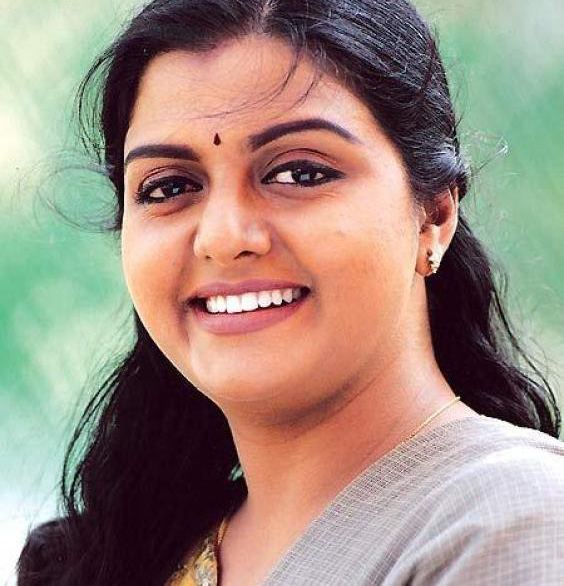 Bhanupriya smiling while wearing a gray blouse, necklace, and earrings