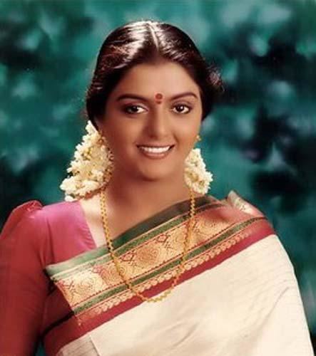 Bhanupriya smiling while wearing a red blouse, gold necklace, earrings, green, red, and cream dupatta, and gajra on her hair