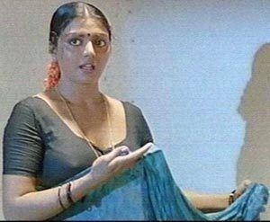 Bhanupriya talking to someone while holding a blue cloth and wearing a gray blouse, necklace, and bracelet