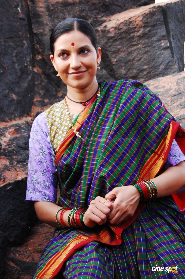 Bhavana Ramanna wearing earrings, necklace, bracelets, and colorful dress.