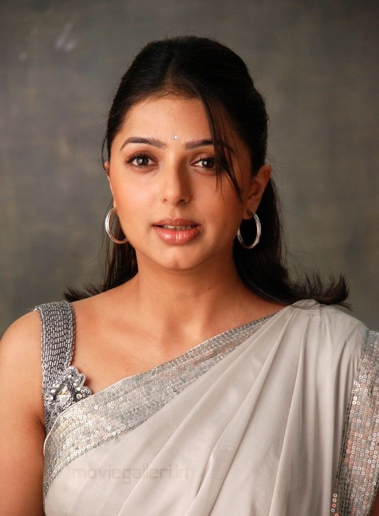 Bhumika Chawla with a tight-lipped smile while wearing a hoop earrings and gray dress with sequins