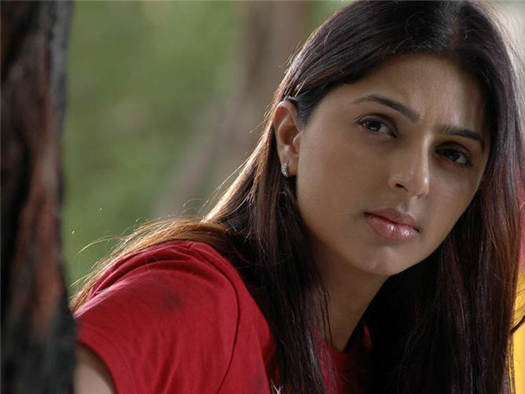 Bhumika Chawla looking afar while wearing a red blouse and earrings