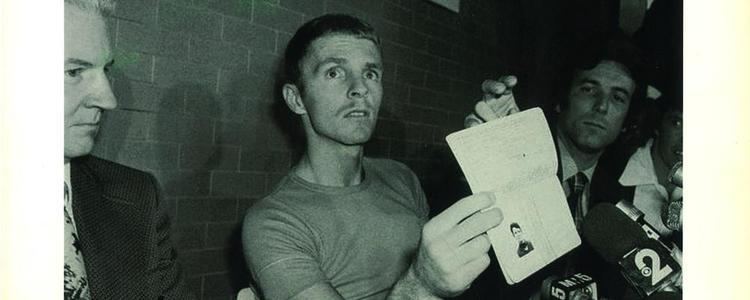 Billy Hayes showing his new passport while he is wearing a t-shirt