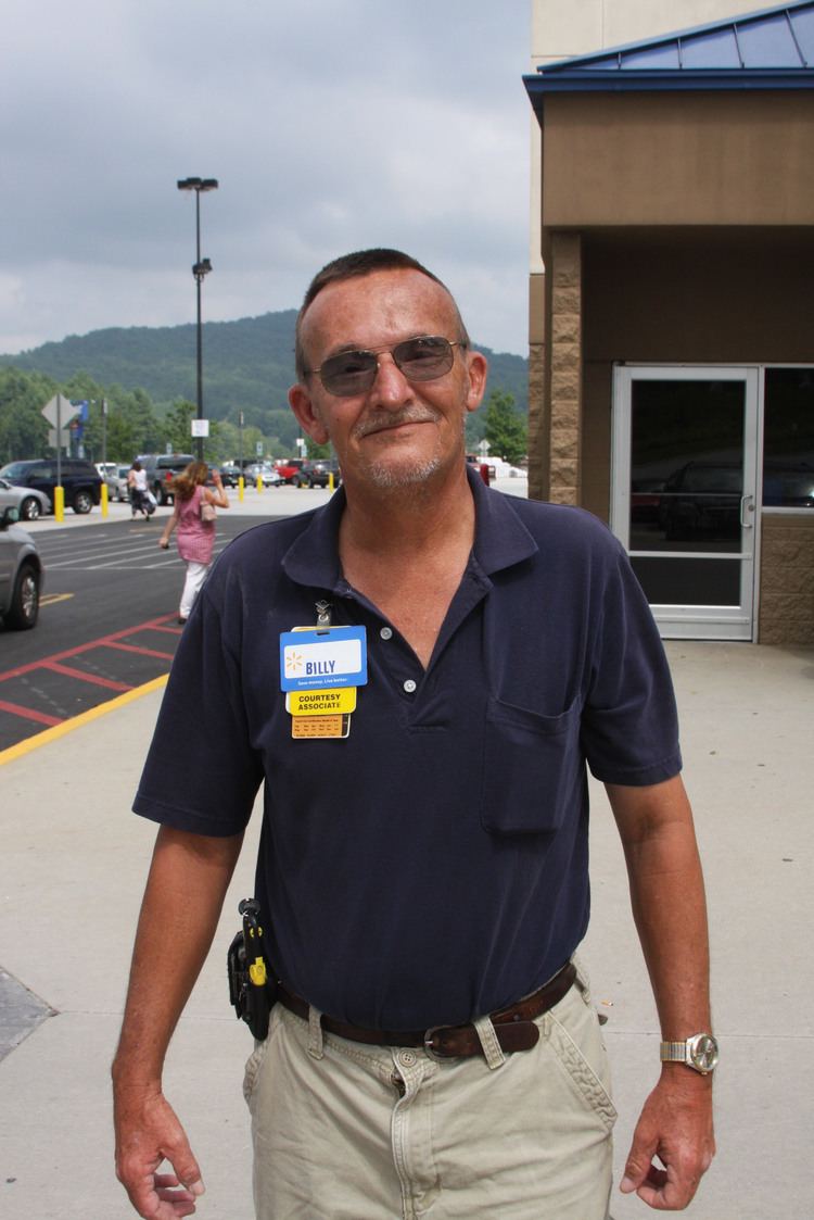 Billy Redden smiling and wearing a blue shirt, white pants and sunglasses