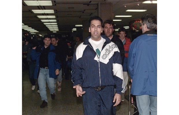 Bindy Johal walking in a crowded place while wearing a white and blue Adidas jacket, white inner shirt, and blue pants