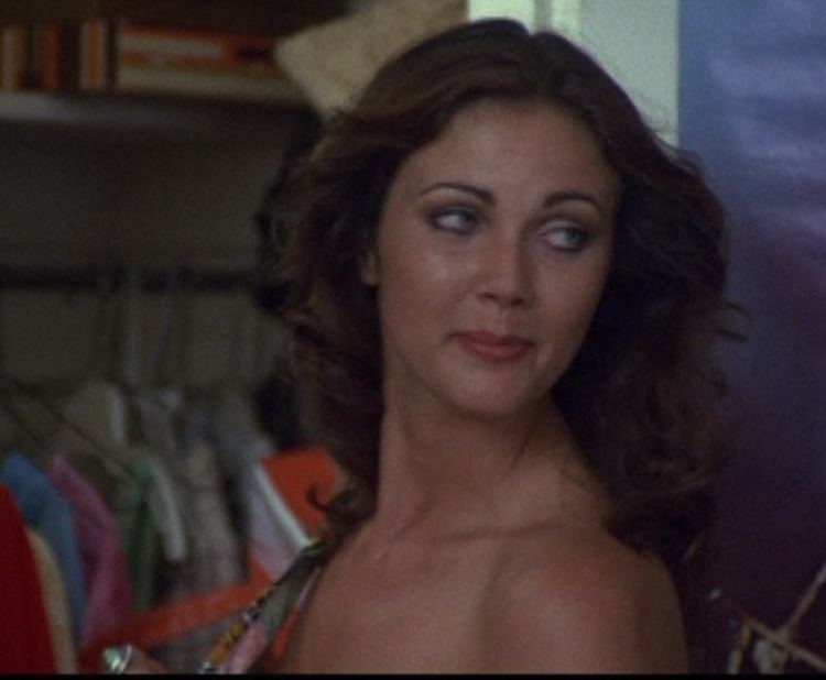 Lynda Carter with a tight-lipped smile while looking at the back in a scene from the 1976 film, Bobbie Jo and the Outlaw