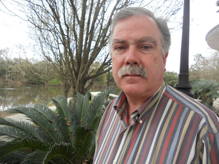 Bobby DeLaughter with mustache and wearing colorful striped long sleeves