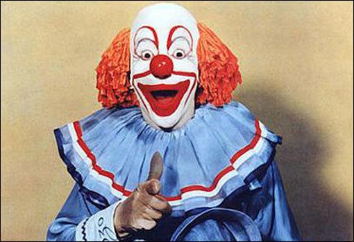 Bozo the Clown smiling while pointing his finger and wearing a blue, red, and white costume