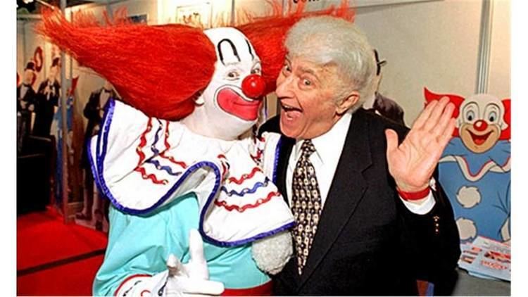 Bozo the Clown smiling with Larry Harmon while wearing a neck ruffle collar and sky-blue long sleeves
