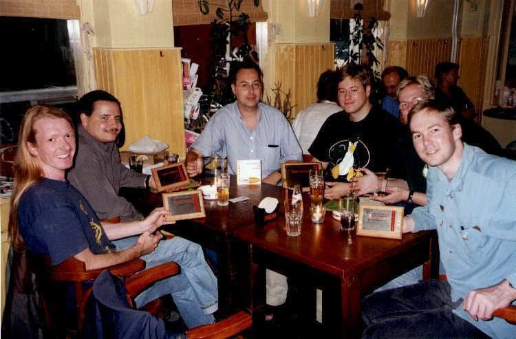 Bram Moolenaar drinking beer with his friends, wearing eyeglasses and a gray polo shirt.