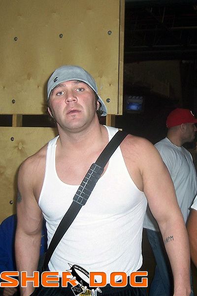 Branden Lee Hinkle wearing a white sando, gray cap, and black shoulder bag