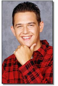 Brandon Call smiling and wearing red checkered long sleeves while holding his chin.