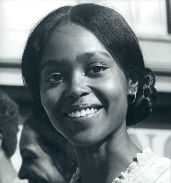 A younger Brenda Sykes smiling with her hair arranged.
