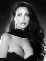 Brenda Venus with a fierce look, with long curly hair, wearing a black tube dress, and black scarf.