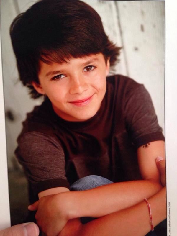 Brent Rivera smiling with crossed arms on top his leg in his childhood picture