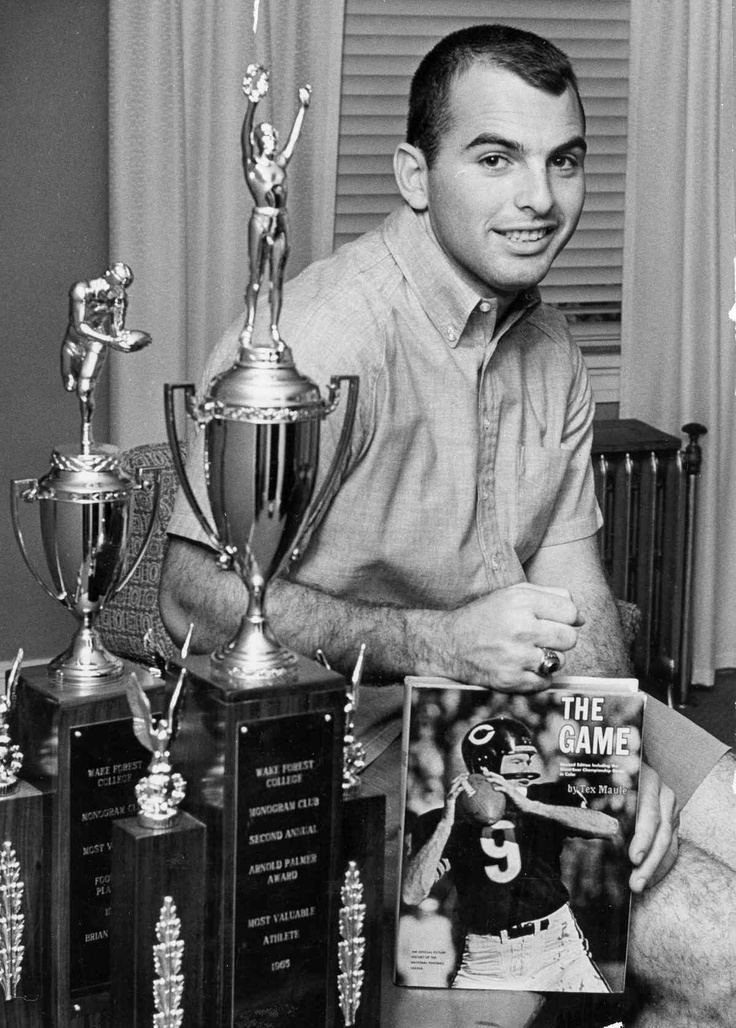 Brian Piccolo smiling next to the trophies he won and holding a magazine where he was featured.