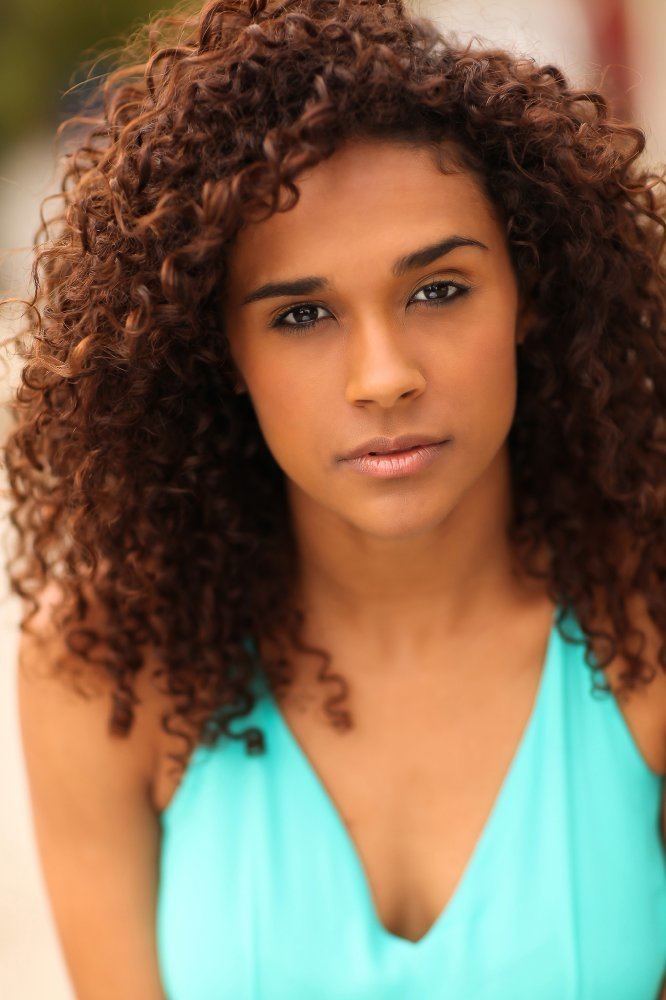 Briana Henry with curly hair while wearing a sky-blue sleeveless top