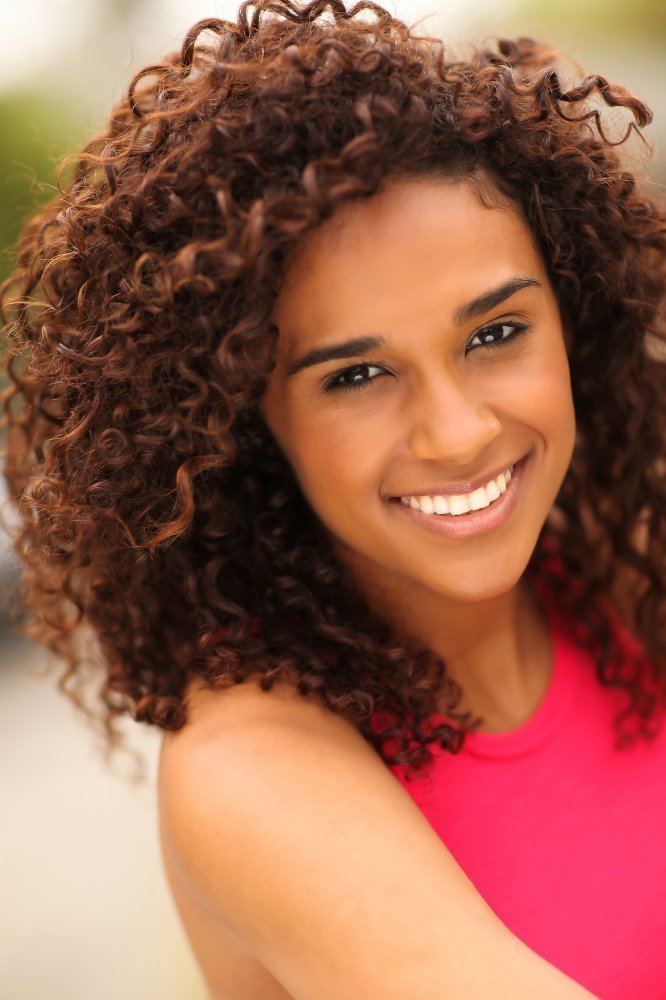 Briana Henry with a big smile and curly hair while wearing a pink sleeveless top